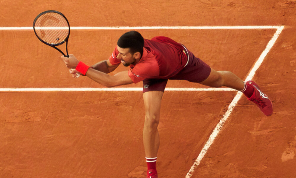 Novak Djokovic returning a tennis serve with his backhand at the 2024 French Open