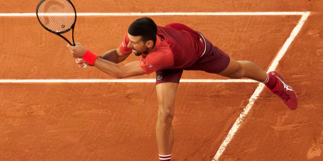 Novak Djokovic returning a tennis serve with his backhand at the 2024 French Open