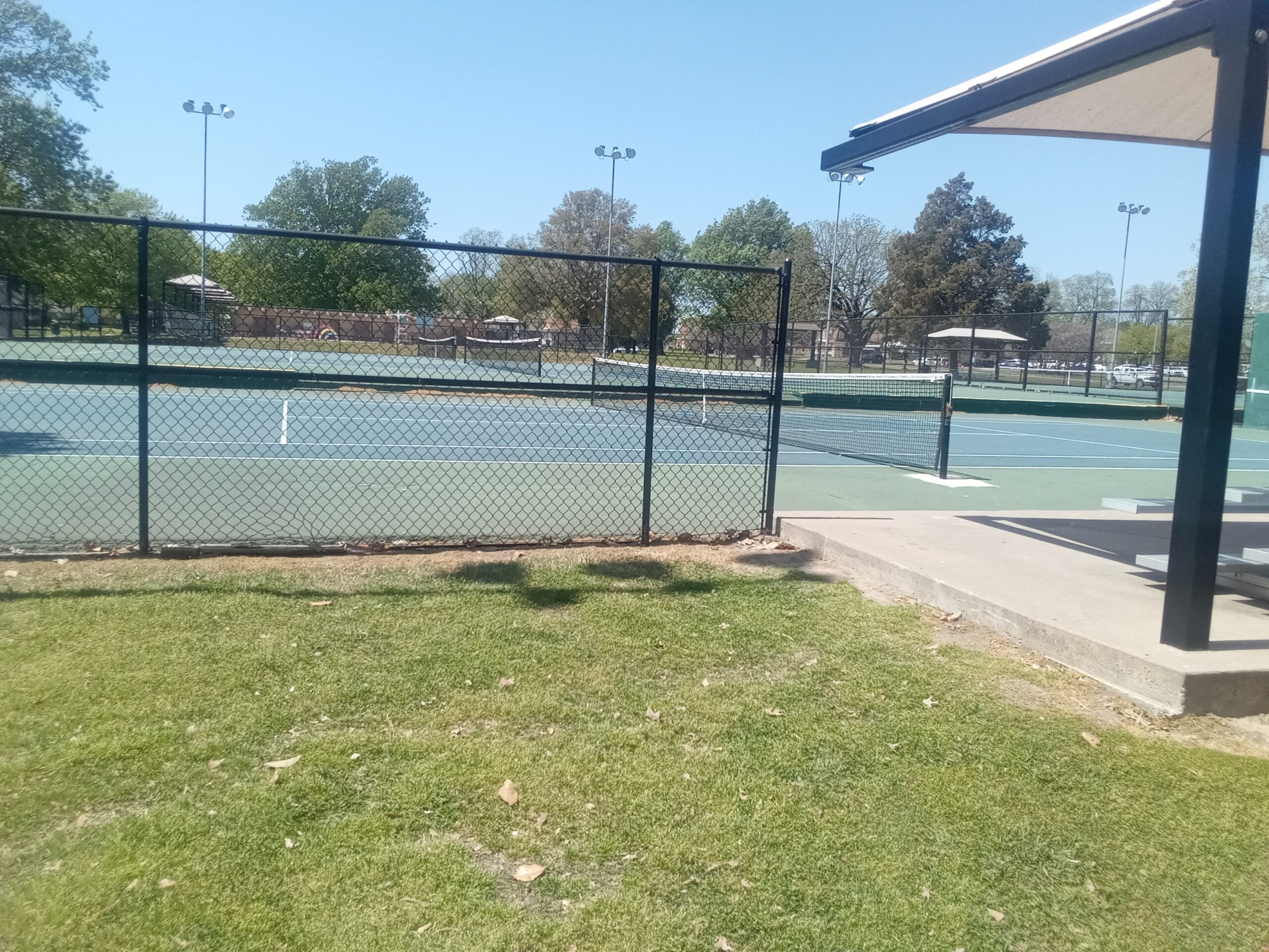 Outdoor tennis courts with net and white boundary markings