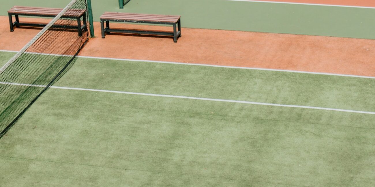 Empty green and orange tennis courts illustrating a match not started after a walkover