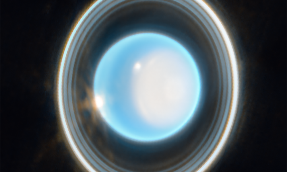 Authentic 2023 James Webb NIRCam Uranus image showing a light-blue planet, white north polar cap, thin nested vertical-looking rings and bright storm clouds
