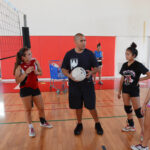 Volleyball coach with a ball explaining tactics to players during a genuine indoor team practice