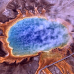 Real aerial photo of Grand Prismatic Spring in Yellowstone with vivid blue central pool orange microbial mats steam and boardwalk