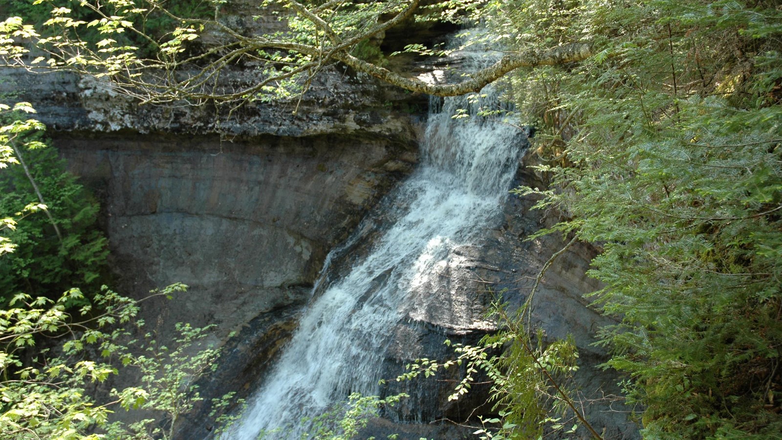 Actual NPS photograph of Chapel Falls at Pictured Rocks, flowing in a narrow waterfall over a slanted sandstone cliff