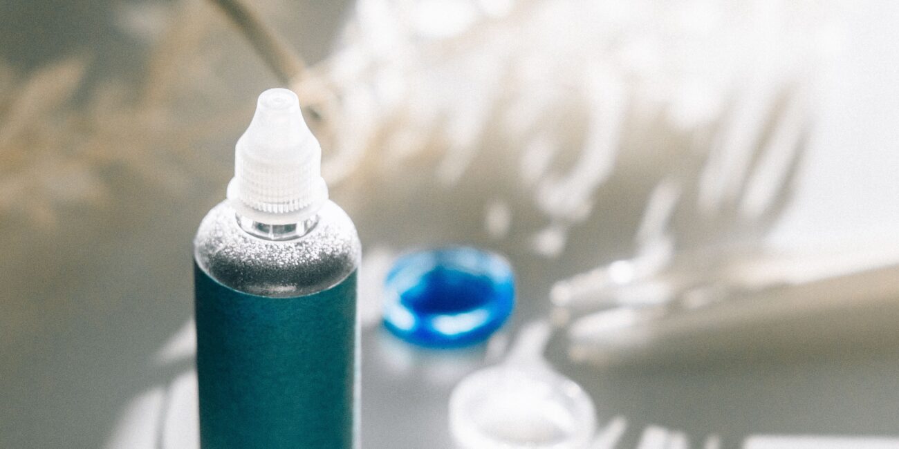 Unbranded eye care drop bottle beside a contact lens case
