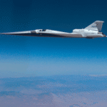 NASA X-59 experimental airplane in flight above the desert and clouds