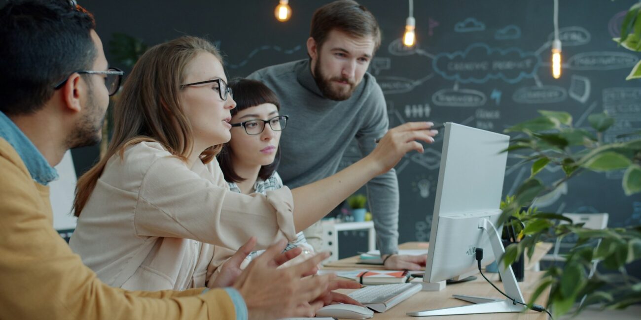 Team collaborating around a computer for the OpenAI and Atlassian partnership article