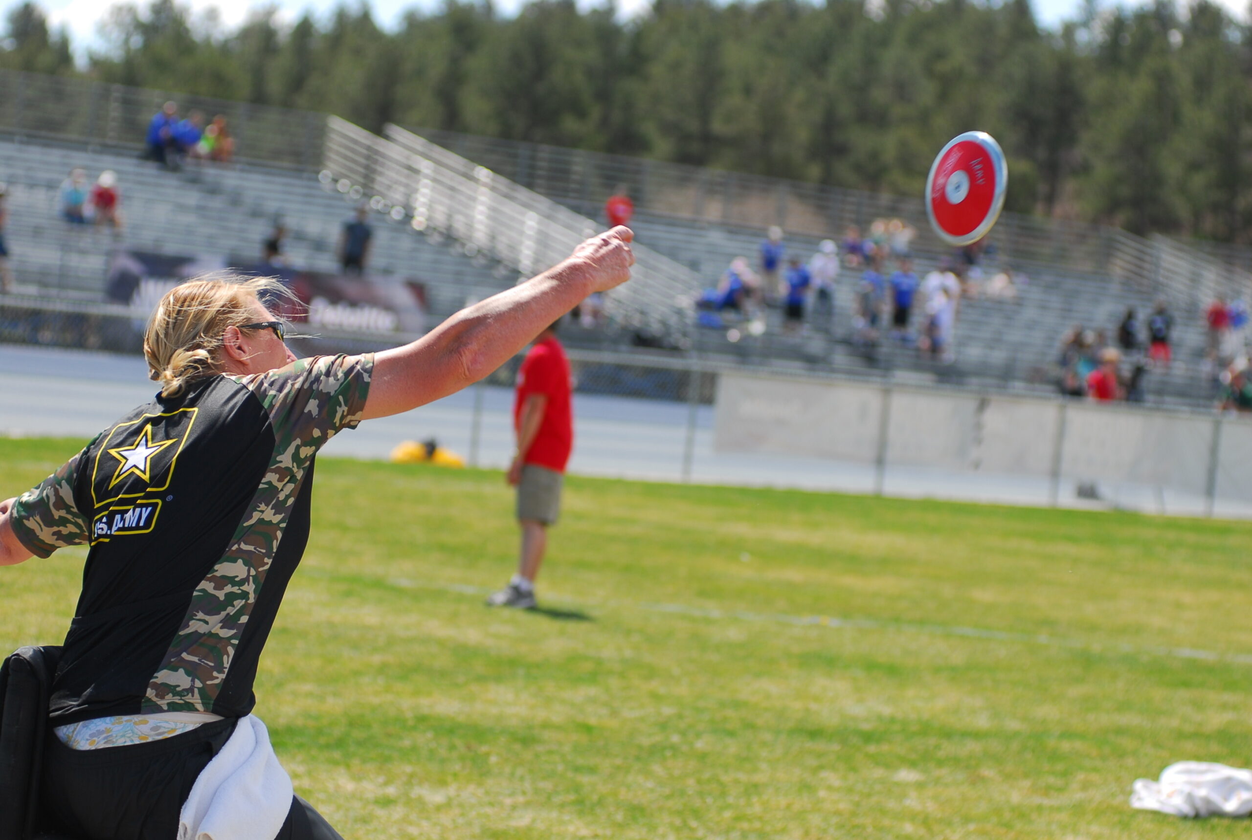 Actual U.S. Army photograph of veteran Chanda Gaeth throwing a discus from a seated position at the 2013 Warrior Games adaptive track-and-field event